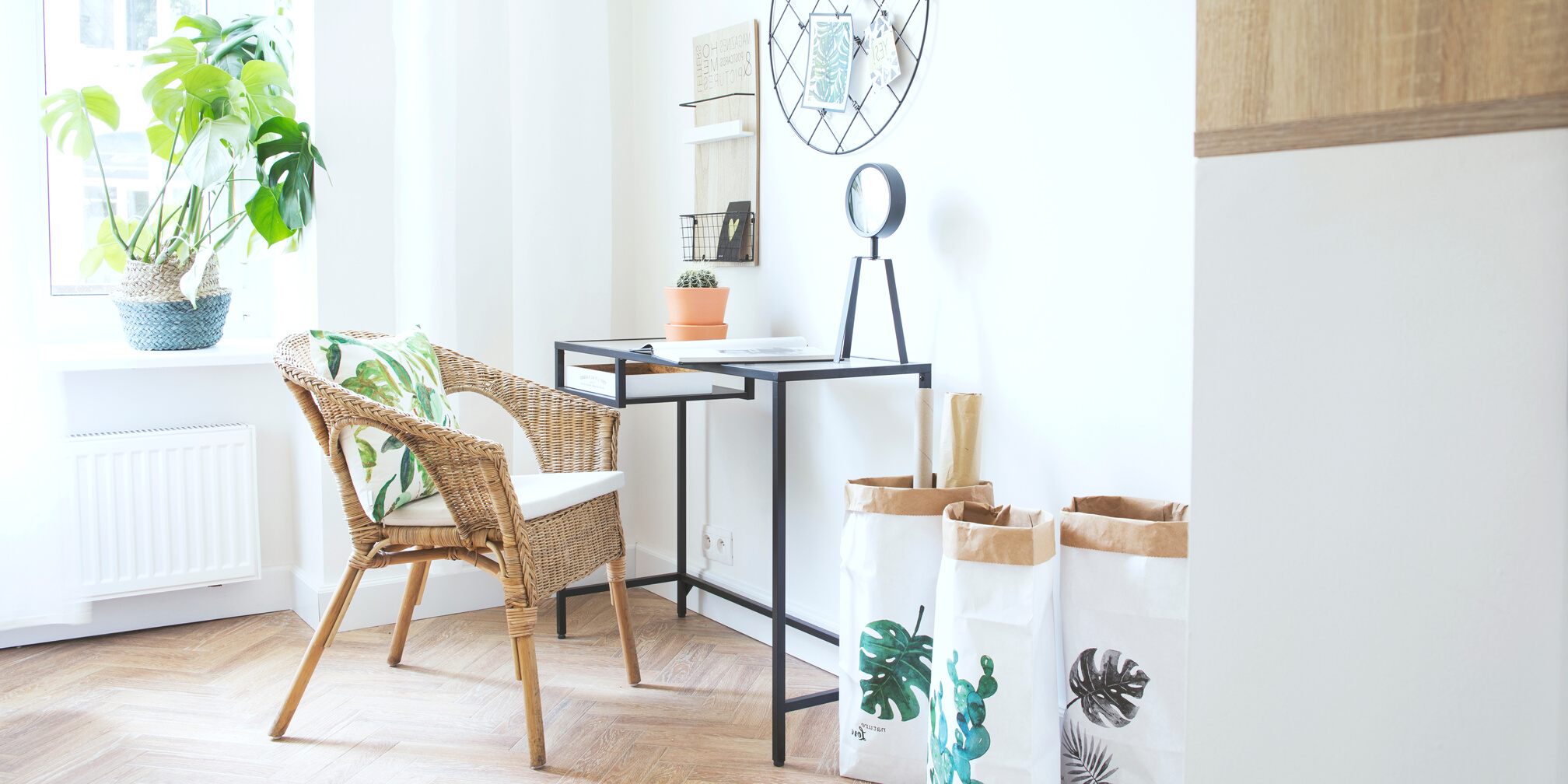 Stylish scanidinavian interior of home office with glass table, design clock paper bags and plants. Design space with wooden brown parquet.